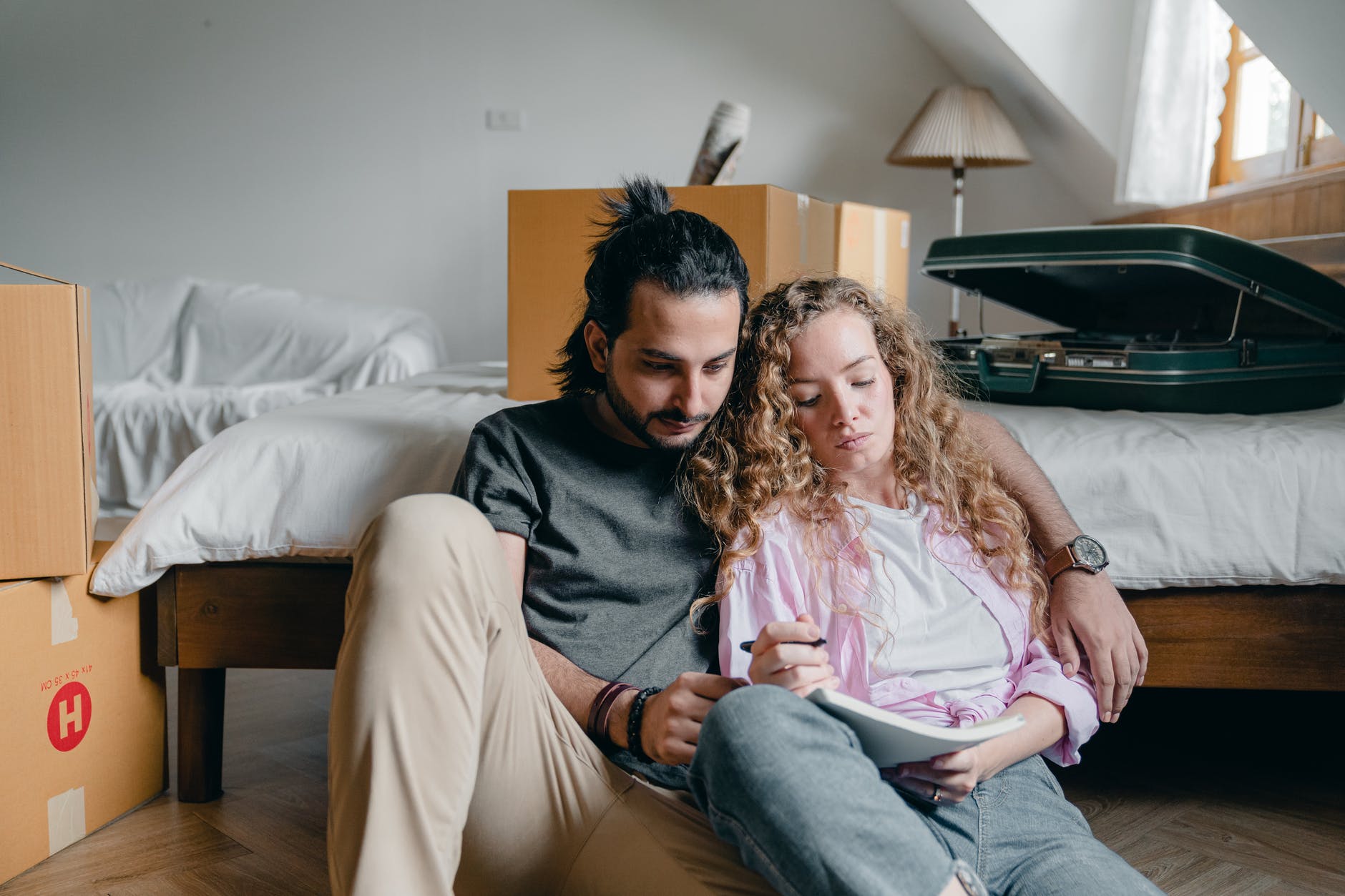 serious couple taking notes and sitting together near bed
